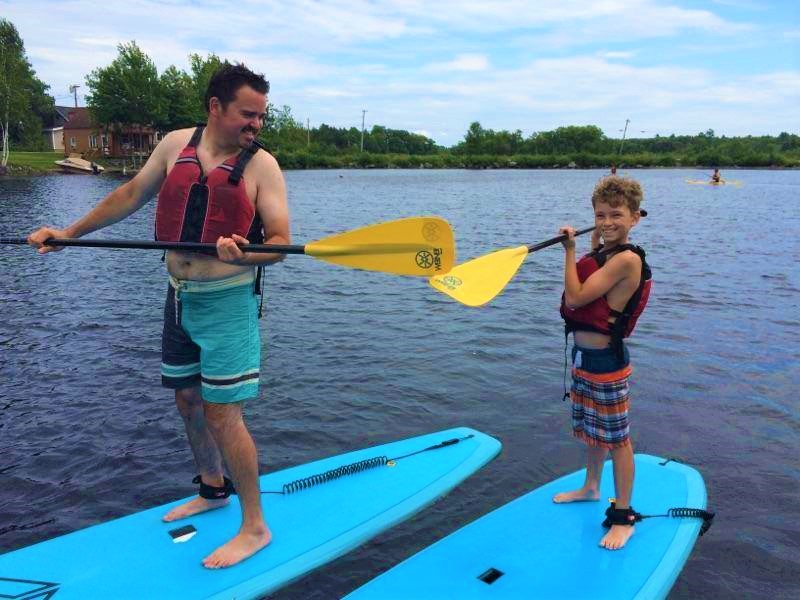 kid paddleboarding with parent